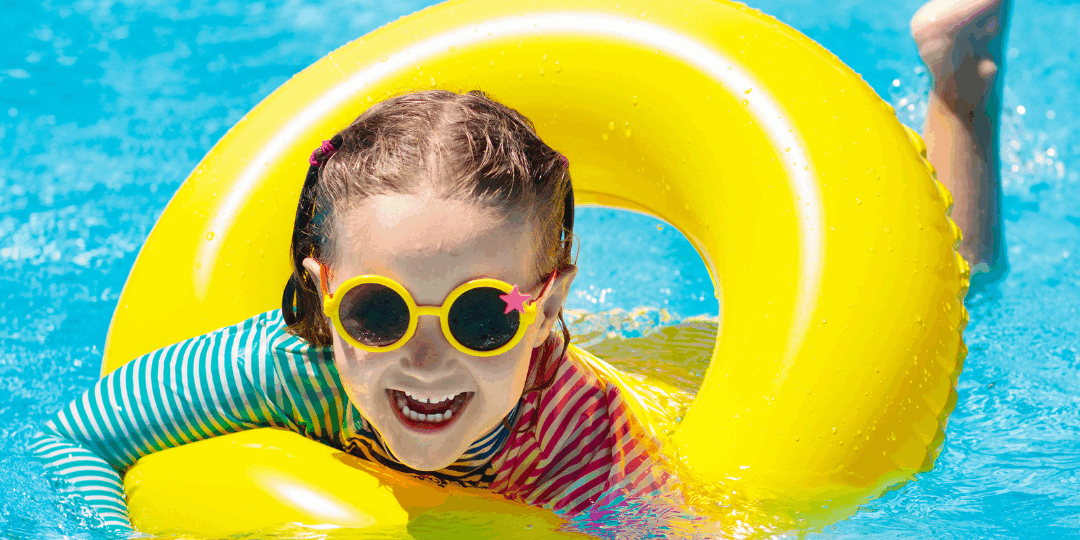 Young girl laughing in a pool with a yellow float ring during summer break in Olathe, KS